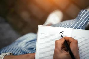 a woman's hand with a pen makes a note in a blank notebook photo