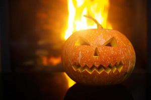 espeluznante calabaza de halloween cerca de una chimenea. fuego en el fondo. foto