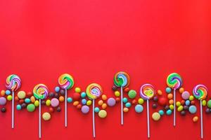Creative flat layout of Rows of various candies on a red background and copy space on top photo