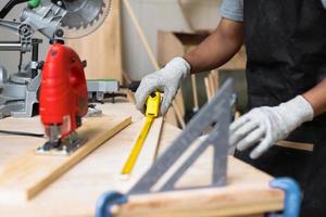 Hand of carpenter working on workshop table using measuring tools photo