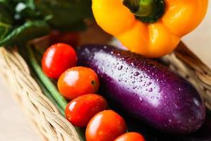primer plano de coloridas verduras frescas en el mimbre de ratán en la mesa de madera foto