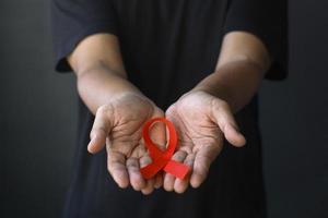 día mundial del sida y día mundial de la diabetes con manos masculinas sosteniendo una cinta roja de concientización sobre el sida. concepto de salud y medicina.