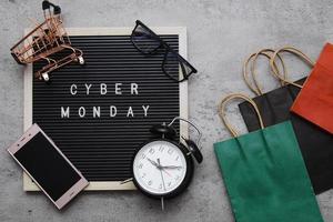 Creative flat lay promotion composition Cyber Monday sale text on letter board with alarm clock goodie bag and gadget photo