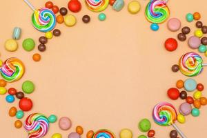 Blank circular frame made with various of colorful candy on cream background. Flat lay, top view photo