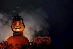 concepto de fondo oscuro de halloween con linterna brillante y calabazas con humo foto