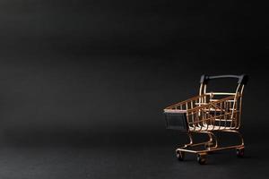 Miniature shopping chart or trolley isolated on black background with copy space photo