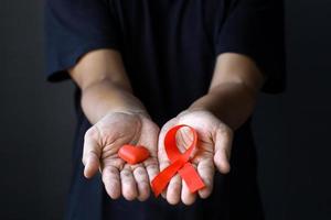 World Aids Day and World Diabetes Day with male hands holding red AIDS awareness ribbon. Healthcare and medicine concept. photo