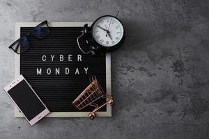 Creative flat lay promotion composition Cyber Monday sale text on letter board with alarm clock goodie bag and gadget photo