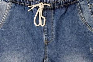 The background texture on the front of the jeans has a drawstring at the waist and a front pocket photo