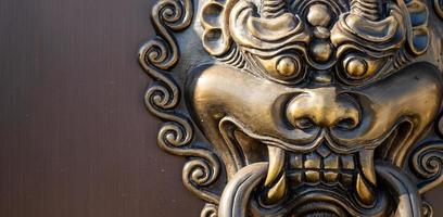 Metal dragon head door knocker in front of the entrance of Chinese temple, art related to religious beliefs