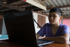 niño estudiando en línea con una computadora portátil en un escritorio en el campo foto