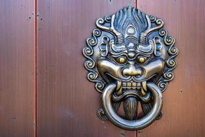 Metal dragon head door knocker in front of the entrance of Chinese temple, art related to religious beliefs