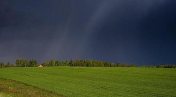 a lonely house in the middle of a green field and a stormy sky photo