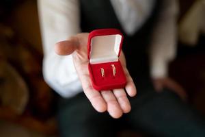 Gold wedding rings in a red box in your hand photo