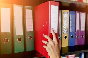 the girl in the archive puts a folder with documents on the shelf close-up photo