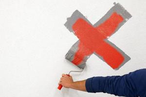 worker drew a cross with a roller on the white wall photo