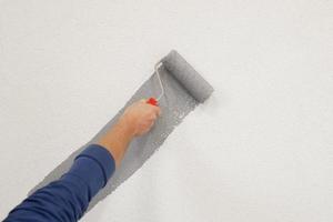 hand with paint roller in hand, painting a wall photo
