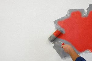 painting walls with a roller in his left hand. photo