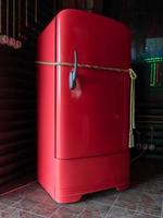 refrigerador vintage rojo atado con una cuerda. foto
