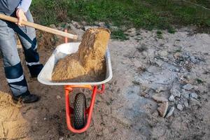 trabajador vierte arena en una carretilla foto