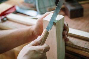 carpintero usando sierra japonesa o sierra de tracción, corte transversal en madera sobre mesa, concepto de carpintería