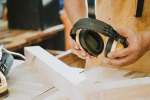 carpenter holding Protective ear muffs in the workshop ,DIY maker and woodworking concept. selective focus photo