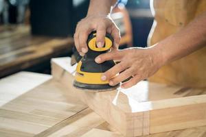 carpenter use random orbit sander or palm sander polishes wooden in the workshop ,DIY maker and woodworking concept. selective focus