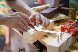 carpintero usando un lápiz rojo para dibujar una línea en la madera en el taller, fabricante de bricolaje y concepto de carpintería. enfoque selectivo foto