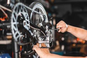 el mecánico de bicicletas ajusta el desviador trasero y repara la bicicleta en el taller. ,concepto de reparación y mantenimiento de bicicletas foto