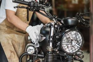 Biker man cleaning motorcycle , Polished and coating wax on fuel tank at garage. motorcycle maintenance and repair concept. photo