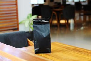 Photo of coffee packaging standing pouch size 1 Kg on the cafe table. suitable for mock up label stickers, coffee variant packaging stickers or etc.