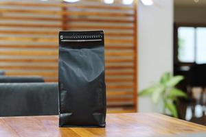 foto de una bolsa de pie de embalaje de café de 1 kg sobre la mesa del café. adecuado para etiquetas adhesivas simuladas, etiquetas adhesivas de embalaje de variantes de café, etc.