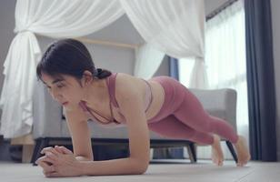 Fit woman doing plank exercise, workout at home.