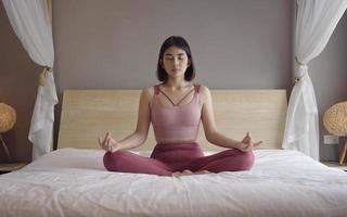 Woman in sportsware practice yoga lotus pose to meditation at home, Wellness woman doing yoga for breathing and meditation comfortable and relax. photo