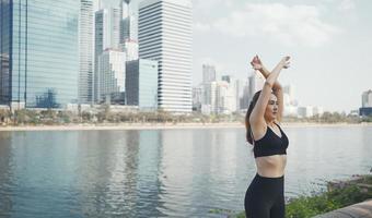 Sport woman wearing wireless headphones and stretching muscles before running in city, warmup exercise. photo