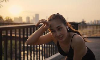 Young woman athlete running resting exhausted after a cardio workout exercise in the urban city sunset. Jogging lifestyle healthy. photo