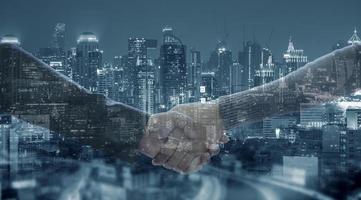 Close up of business handshake for successful of investment deal and city night background, teamwork and partnership concept. photo