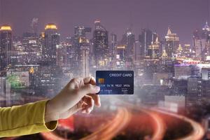 Business financial ideas concept with hand hold credit card and city building background. photo
