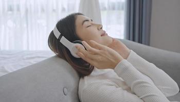 Woman wear wireless headphones enjoy good meditative music. Serene young woman in headset relax listen to audiobook with closed eyes.