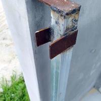 Focus on the rusted steel of the building's fence gate installation. photo