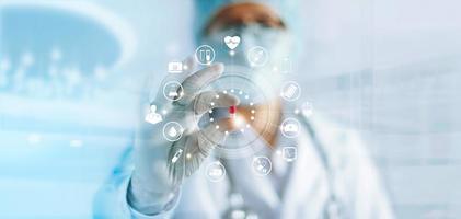 Medicine doctor holding a color capsule pill in hand with icon medical network connection on modern virtual screen interface in laboratory background, medical technology network concept photo