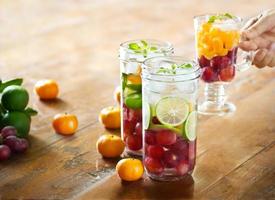 Glass refreshing drink of mix fruits on wooden background, infusion water, healthy concept