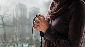 mujer rezando con rosario y cruz de madera en el fondo de la iglesia. concepto de esperanza foto