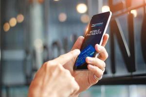 Man using mobile payments online shopping network connection on screen, Coffee shop background. All on screen and credit card are design up. photo