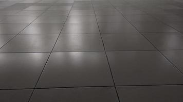 White ceramic tile floor in dim light room with soft light and shadow from outside of the building photo