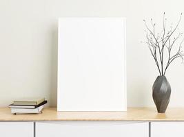cartel blanco vertical minimalista o maqueta de marco de fotos en una mesa de madera con libros y jarrón en una habitación. representación 3d