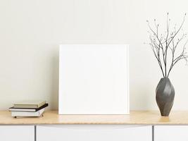 Minimalist square white poster or photo frame mockup on wood table with books and vase in a room. 3D Rendering.