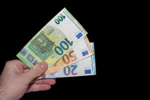mano sujetando la inflación de los billetes de tres euros en el mundo en el mercado financiero con negro foto