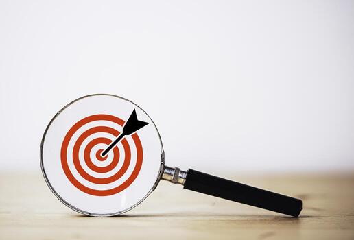 Dartboard and arrow inside of magnifier glass on table for setup and focus business objective target concept. photo