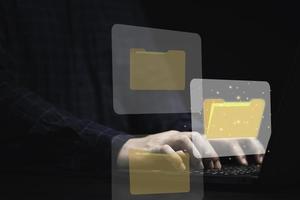 hombre de negocios que usa una computadora portátil con un gráfico de carpeta virtual para el concepto de gestión de bases de datos de documentos en línea. foto